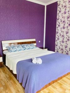 a purple bedroom with a bed with two rolled towels at Mira House in Martvili