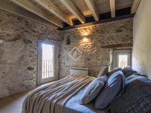 a bedroom with a large bed in a stone wall at Villa Age in Puigcerdà