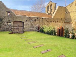 an old stone building with a yard with stepping stones at Villa Age in Puigcerdà