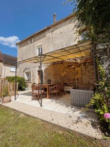 a patio with a table and chairs under a roof at Joli gîte pour 5 personnes : Chez Cherrie in Saint-Julien-de-Lampon