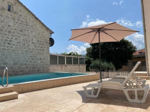 a chair and an umbrella next to a swimming pool at Villa Pul in Risan