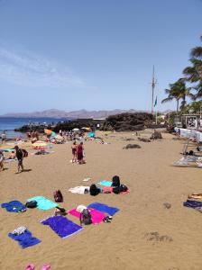 a group of people laying on a beach at Central Apartment 4P Playa Chica Beach 2min WIFI in Puerto del Carmen