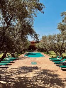 una piscina con tumbonas verdes y árboles en GreenLife Marrakech en Marrakech