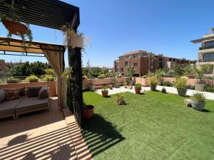 um pátio com relva e um sofá num quintal em Marrakech M Avenue CR 7 appart terrasse em Marrakech