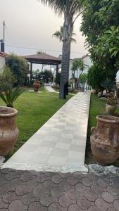 a sidewalk in a park with two large vases at Villa Grazia in Capo Vaticano