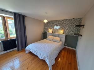 sypialnia z łóżkiem w pokoju z drewnianą podłogą w obiekcie Gîtes Le Lilas - Lac de Pareloup w mieście Canet-de-Salars