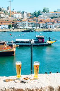 dois copos de cerveja sentados numa mesa ao lado da água em Stay In Apartments no Porto