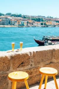 dos vasos de cerveza sentados en una pared con vistas al agua en Stay In Apartments, en Oporto