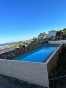 a swimming pool with a retaining wall and the beach at St Ives beach access apartment in Margate