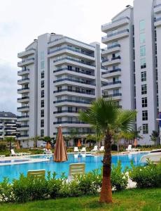 a large apartment building with a palm tree and a swimming pool at Alanya-Avsallar 55m 1+1 in Avsallar