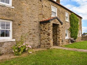 a stone house with a door and a grass yard at High Bank Farm in Cockfield