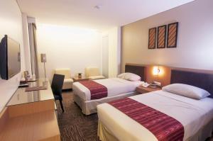 a hotel room with two beds and a television at Cipta Hotel Wahid Hasyim in Jakarta