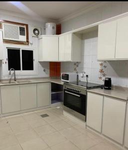 a kitchen with white cabinets and a stove top oven at شقق بدور أرضي in Al-Salam