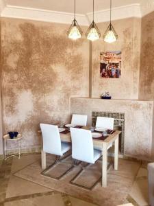 a dining room with a table and white chairs at Appartement avec vue sur l'Atlas et piscine in Marrakesh