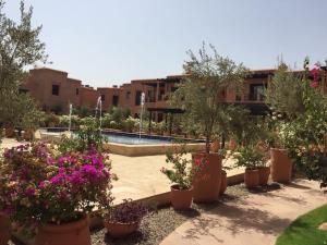 une cour avec des plantes en pot et une piscine dans l'établissement Appartement avec vue sur l'Atlas et piscine, à Marrakech