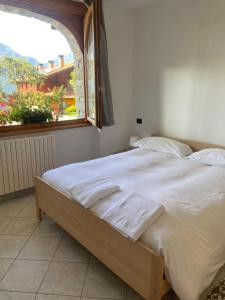 a bedroom with a large white bed with a window at Casa Camilla in Colico