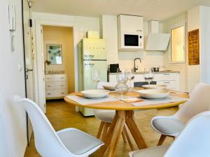 a kitchen with a wooden table and white chairs at Lancón Boutique- Precioso apartamento a 150 m a pie de playa Lancón- Carboneras in Carboneras