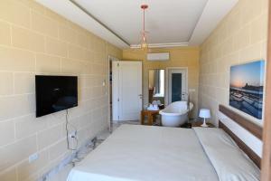 a bedroom with a bed and a tv and a tub at Azure W B&B in San Lawrenz