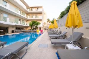 een rij stoelen en parasols naast een zwembad bij Dimitrios Beach Hotel Adults Friendly 14 plus in Rethimnon