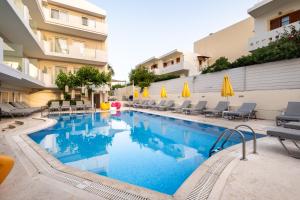 una piscina con sillas y sombrillas junto a un edificio en Dimitrios Beach Hotel Adults Friendly 14 plus en Rethymno Town