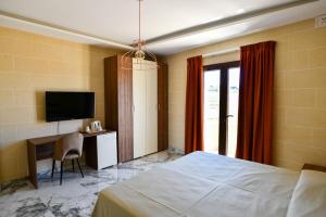 a bedroom with a bed and a desk and a television at Azure W B&B in San Lawrenz