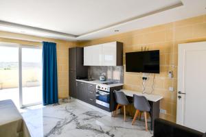 a kitchen with a table and chairs and a television at Azure W B&B in San Lawrenz