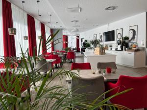 un ristorante con sedie rosse e tavoli in una stanza di DORMERO Hotel Hof a Hof