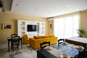 a living room with a yellow couch and a tv at Azure W B&B in San Lawrenz