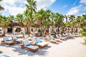 a row of lounge chairs on a beach with palm trees at Superbe, rénové, au calme, plage 200m, terrasse vue Mer! in Rayol-Canadel-sur-Mer