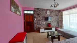 - un salon avec un canapé et un mur en briques dans l'établissement Lux Suites Green City Gardens Syokimau, à Nairobi