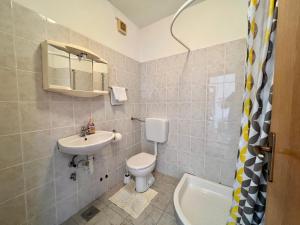 Un baño con inodoro, lavabo y espejo. en Apartmani Bona, en Biograd na Moru