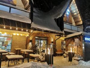 a restaurant covered in snow with tables and chairs at Gościniec Kuźnice in Zakopane