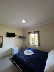 1 dormitorio con 1 cama con manta azul y ventana en Recanto Lua Clara, en Campos do Jordão