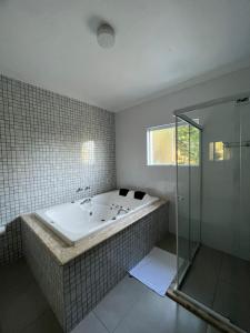 La salle de bains est pourvue d'une baignoire et d'une douche en verre. dans l'établissement Recanto Lua Clara, à Campos do Jordão