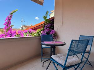una mesa pequeña y sillas en un balcón con flores en Apartmani Bona, en Biograd na Moru