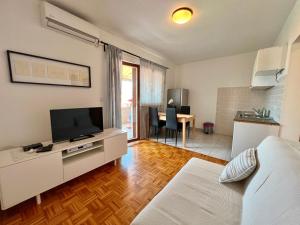 Habitación con cama, TV y mesa. en Apartmani Bona, en Biograd na Moru
