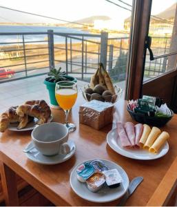 uma mesa com comida para o pequeno-almoço e um copo de sumo de laranja em Balcones del Beagle Apart em Ushuaia
