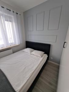 - un lit avec des draps et des oreillers blancs dans une chambre dans l'établissement 60 - Apartamenty Siedlce - Nowy apartament w centrum przy ul 3 Maja 51a, à Siedlce