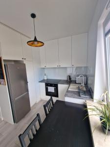 a kitchen with white cabinets and a black table and chairs at 60 - Apartamenty Siedlce - Nowy apartament w centrum przy ul 3 Maja 51a in Siedlce