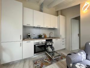 uma cozinha com armários brancos e um forno com placa de fogão em Aquadolce em Baveno