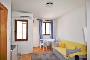 a living room with a yellow couch and a table at Apartmani Bona in Biograd na Moru