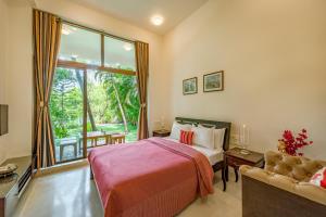 een slaapkamer met een bed, een bank en een raam bij SaffronStays Miraya - Nature Retreat, Pool, Games, Bar in Alibaug in Alibaug