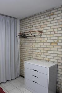 - une commode blanche dans une pièce avec un mur en briques dans l'établissement Casa MAgdeburg II - Central e completa, à Pomerode