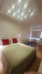 - une chambre avec un grand lit blanc et des oreillers rouges dans l'établissement Hotel Pueblo Huarpe, à San Luis