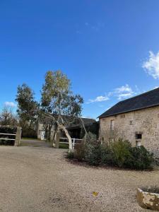 un edificio in pietra con un albero di fronte di Les chambres d'Omaha Beach Etablissement avec deux chambres d'hôtes, petit-déjeuner compris fait-maison et produits locaux a Vierville-sur-Mer