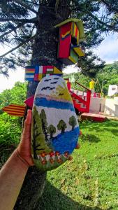 a person holding a painted rock in front of a tree at Cabaña la Hamaca Grande un encuentro con la naturaleza in El Zaino