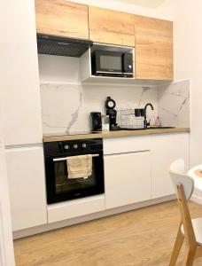 uma cozinha com armários brancos e um forno preto em Maison Coty - Hypercentre/Plage em Le Havre