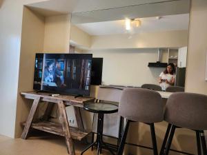 a woman standing in a room with a television on a table at AVIDA TOWER Free Airport Pick up for 3 nights stay or more in Davao City