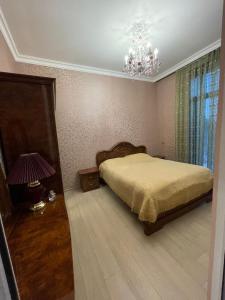 1 dormitorio con cama y lámpara de araña en Veyasum Guest House, en Ganja