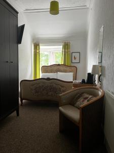 a bedroom with a bed and a chair and a window at Norwood Guesthouse-Loch Lomond in Balloch
